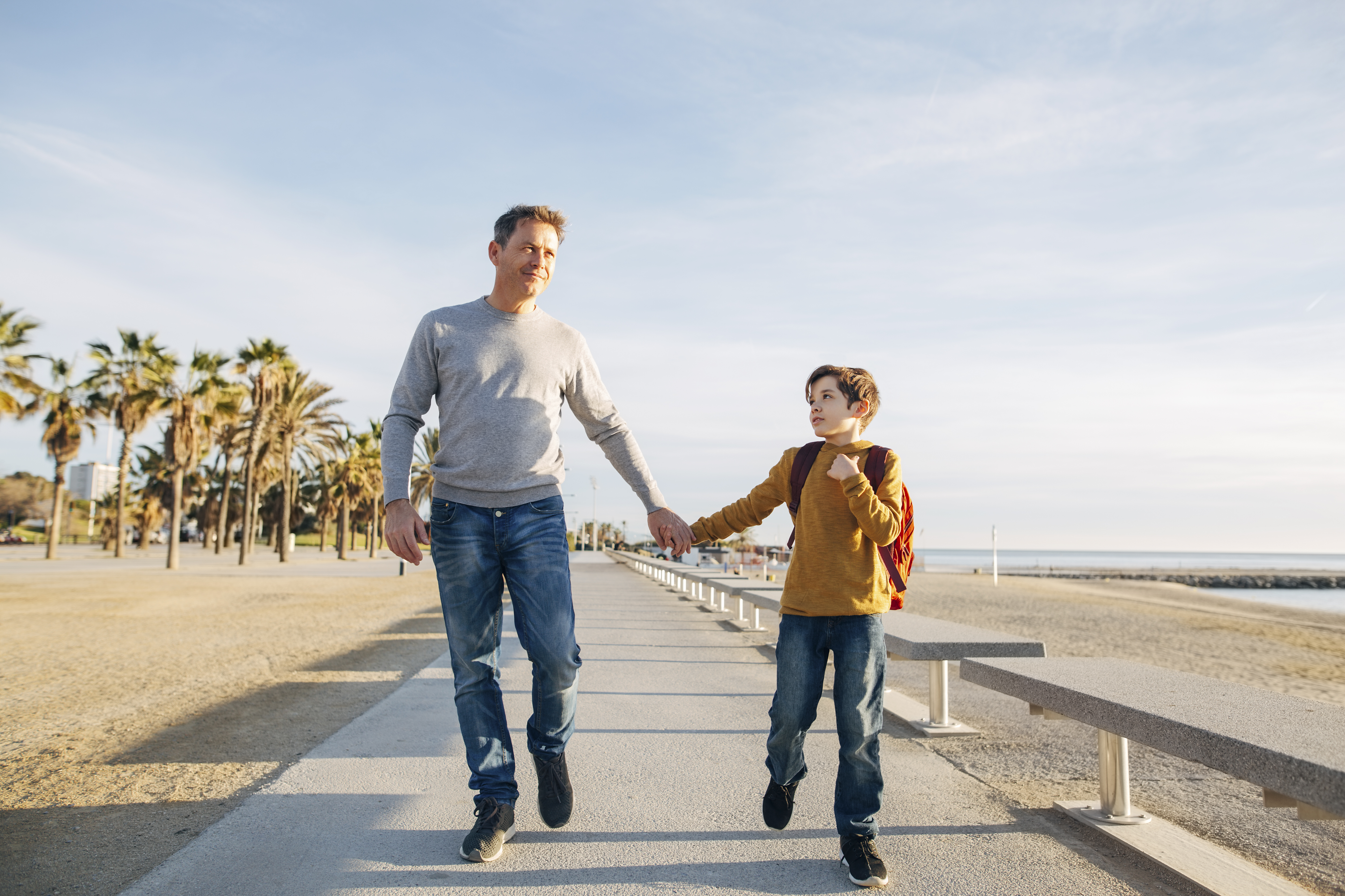 Padre e hijo caminan por la playa en zapatillas